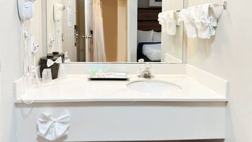 A hotel bathroom with a white sink, a hairdryer, a mirror, and a towel rack.