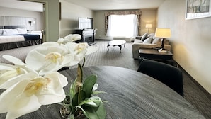 A hotel room with a dining table, a sofa, a TV, and a potted orchid. - BayVue Hotel, Resort and Suites (Ocean Shores)