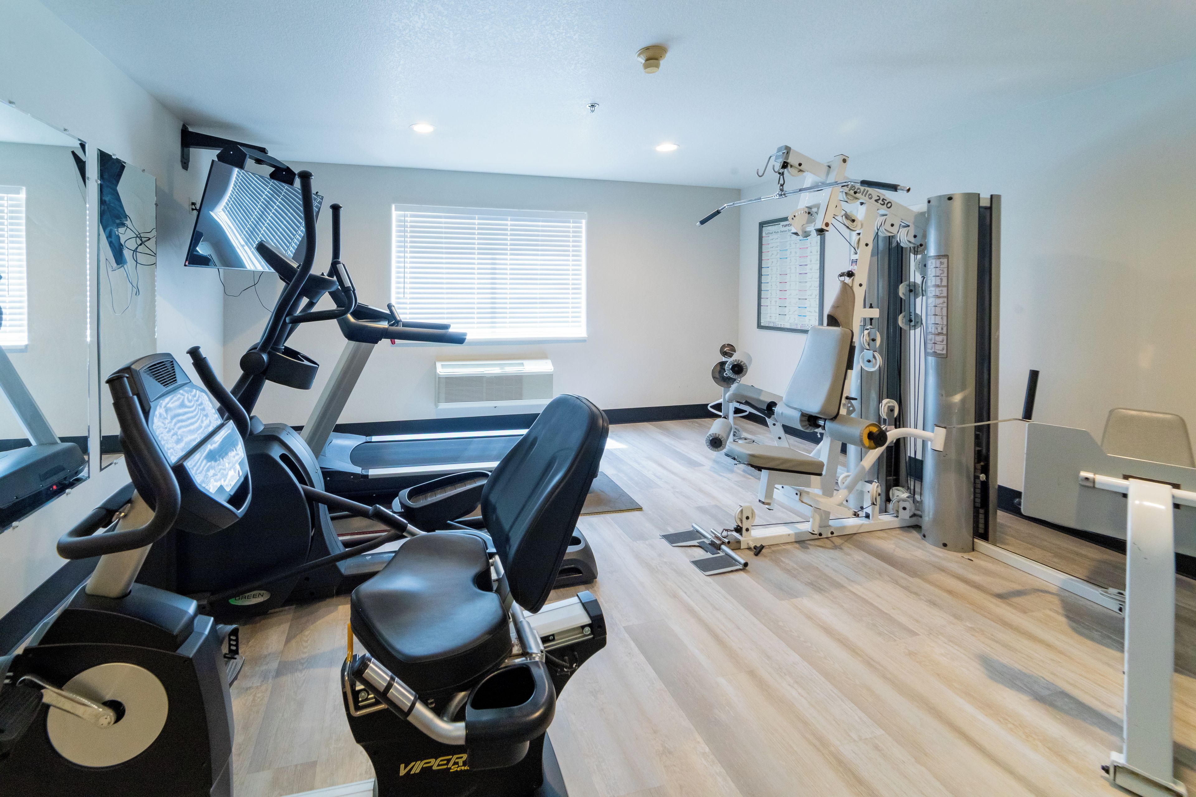 A gym with exercise equipment including a treadmill, stationary bike, and weight machines.