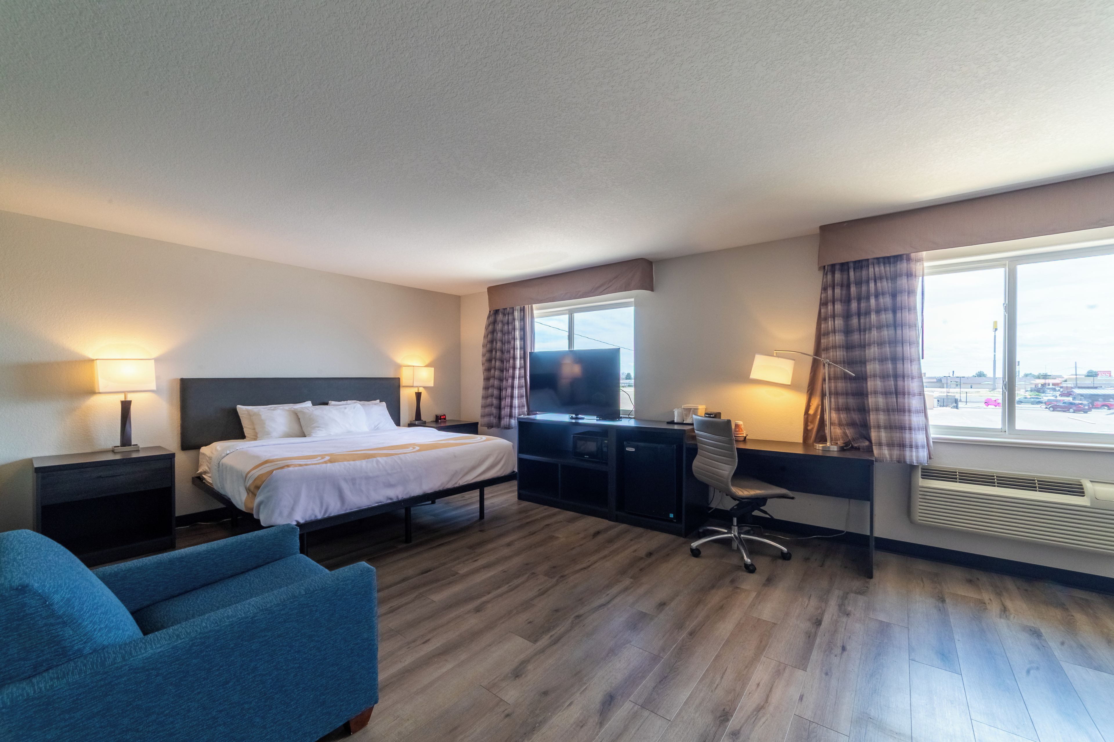 Une chambre d’hôtel avec un lit, un bureau, une chaise et une vue sur la ville par la fenêtre.