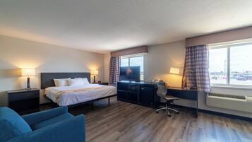 Une chambre d’hôtel avec un lit, un bureau, une chaise et une vue sur la ville par la fenêtre.