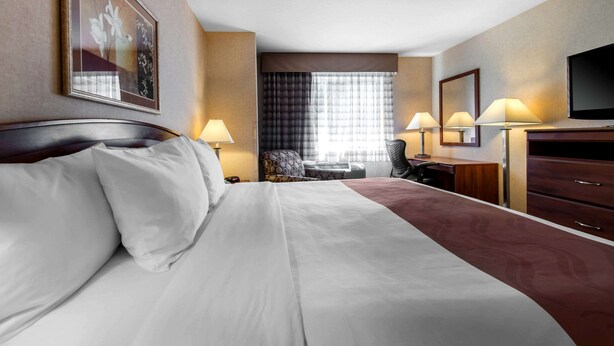 Habitación de hotel con una cama grande, dos lámparas de noche, un escritorio con silla, televisor y ventana con cortinas.