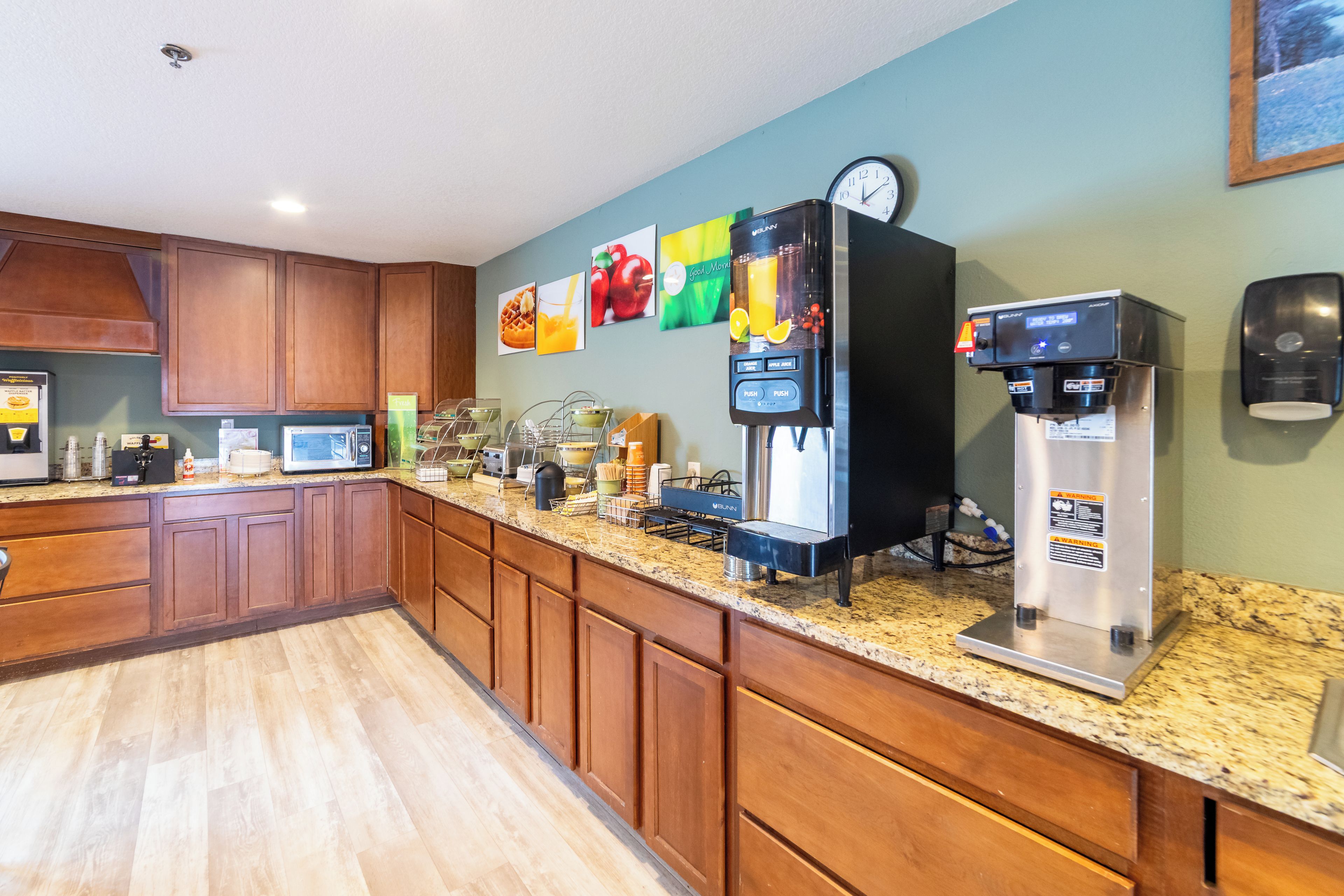 Una cocina con armarios de madera, microondas, cafetera y refrigerador.