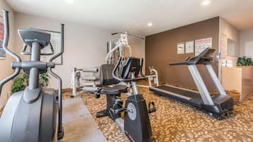 A fitness room with cardio equipment, a treadmill, and a weight machine.