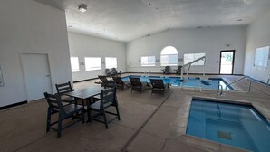 Zona de piscina con sillones de descanso y una mesa, una puerta y ventanas.