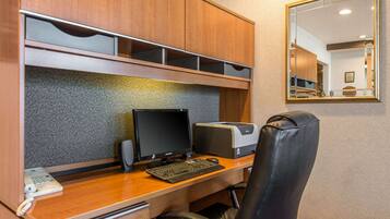 A hotel office with a wooden desk, computer, printer, and a leather chair.