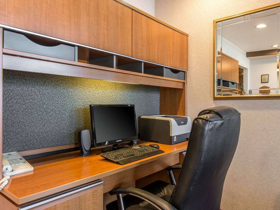 A hotel office with a wooden desk, computer, printer, and a leather chair.