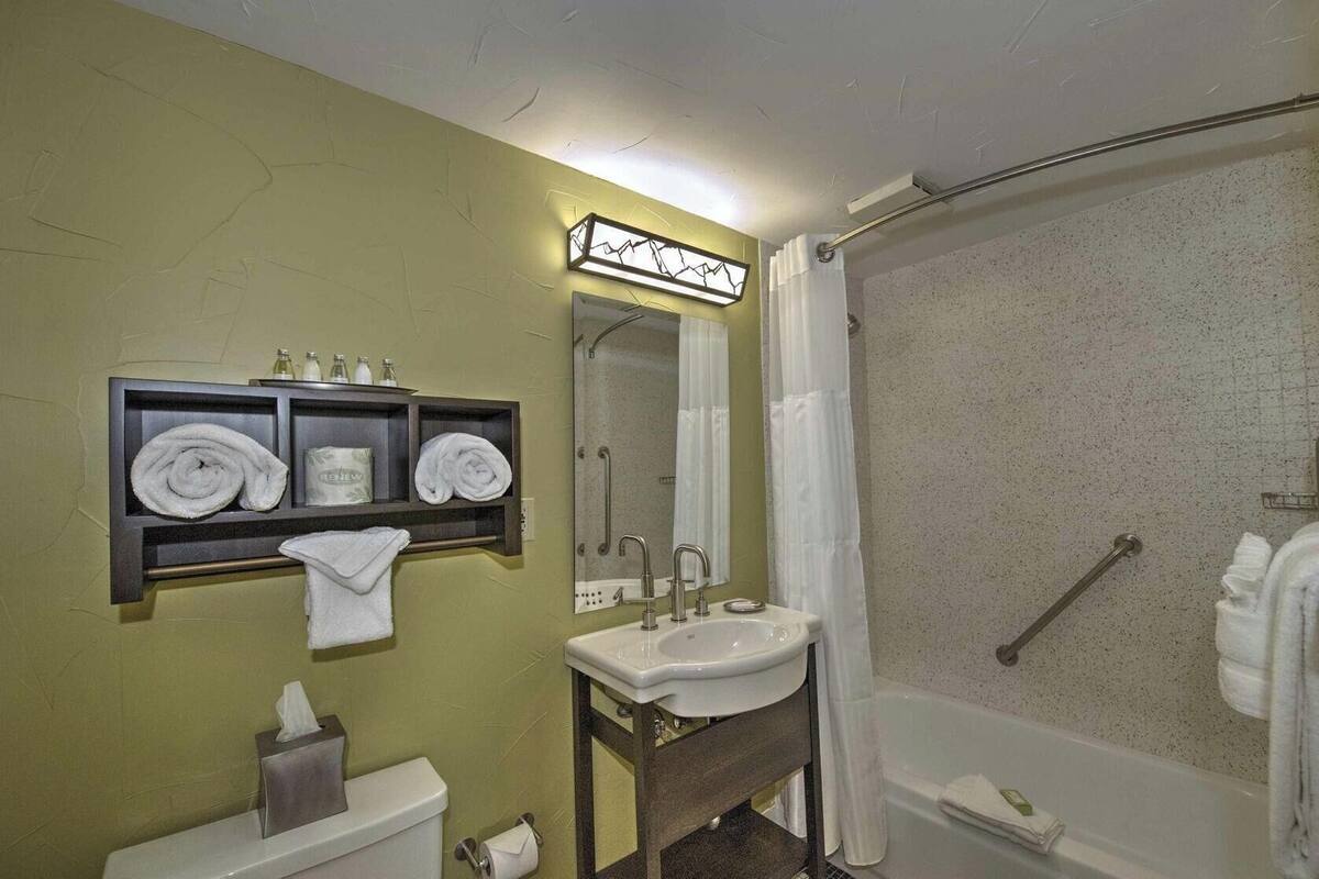 Een badkamer met een wastafel, spiegel, handdoekhouder en douche.