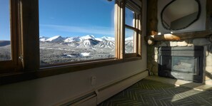 A room with a large window offering a view of snow-covered mountains.