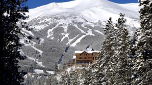 Une montagne enneigée, avec un chalet visible au premier plan.