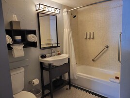 Un baño con ducha, inodoro, lavabo y espejo.