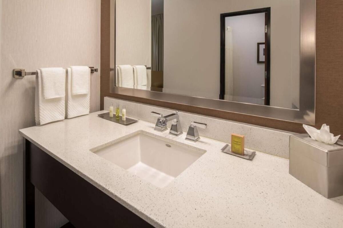 Un baño moderno con un espejo grande, dos lavamanos y un perchero para toallas.