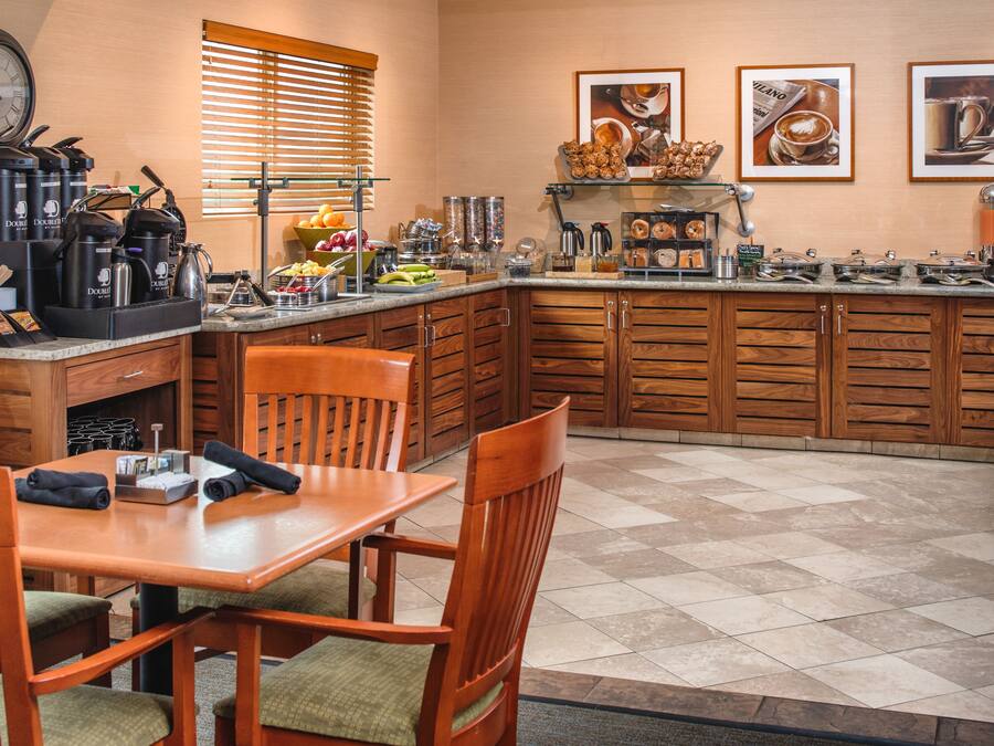 A kitchen with wooden cabinets, a dining table with chairs, and various kitchen appliances and utensils.