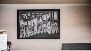 A framed black and white photograph of California with the Capitol building, located in a hotel lobby with a carpeted floor and a reception desk. - Pelican Inn Monterey (Monterey)