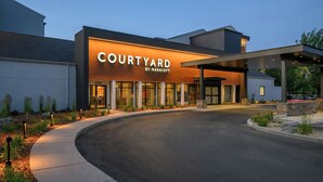Un hôtel Courtyard by Marriott au design moderne, doté de grandes fenêtres et d’un espace d’entrée abrité.