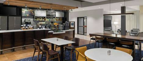A modern bar area with a counter, seating, and a large screen.