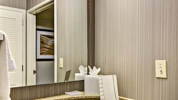 A modern bathroom with a granite countertop, a sink, a mirror, and a towel hanging on the wall.