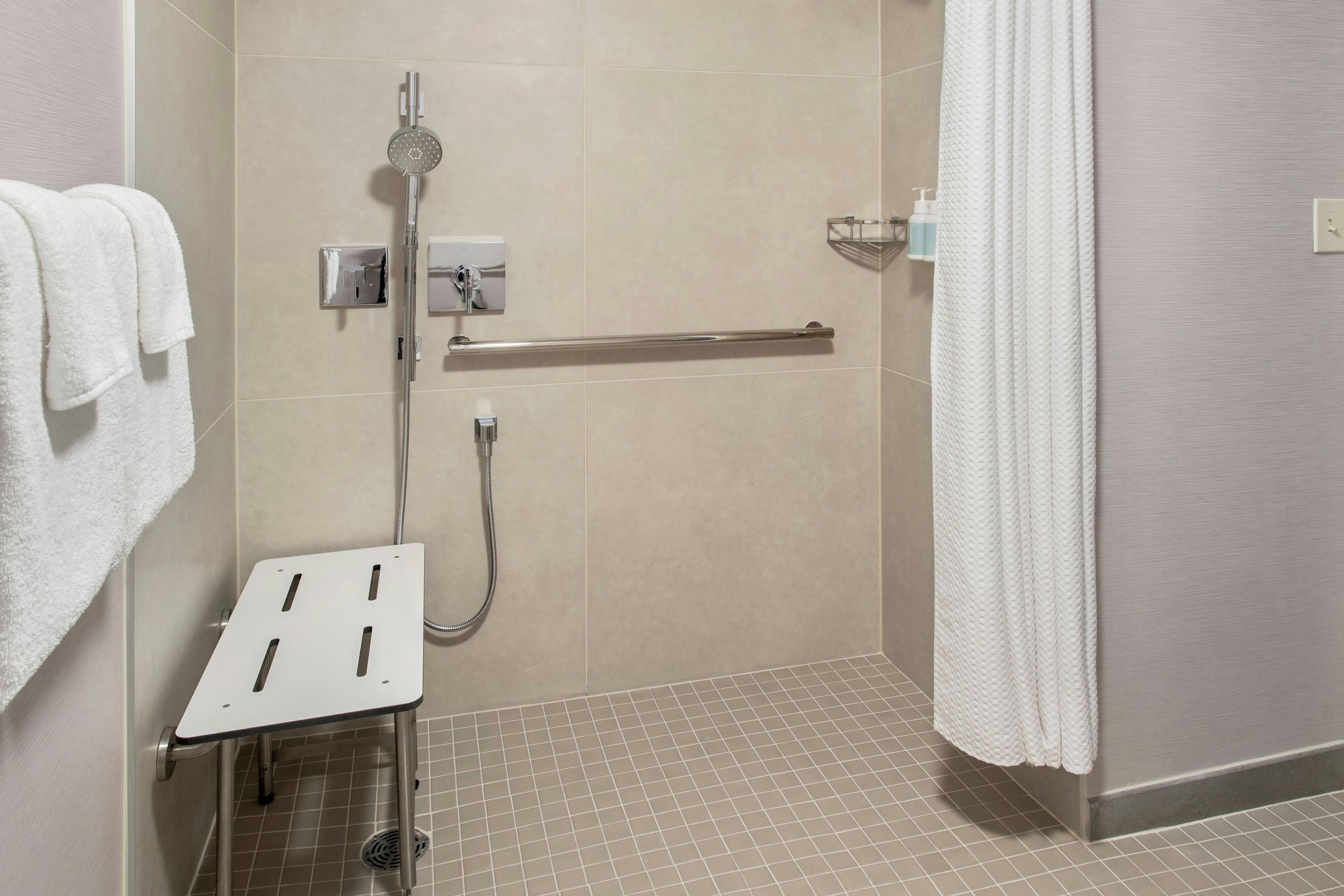 Un baño moderno con ducha, secamanos y barra para toallas.