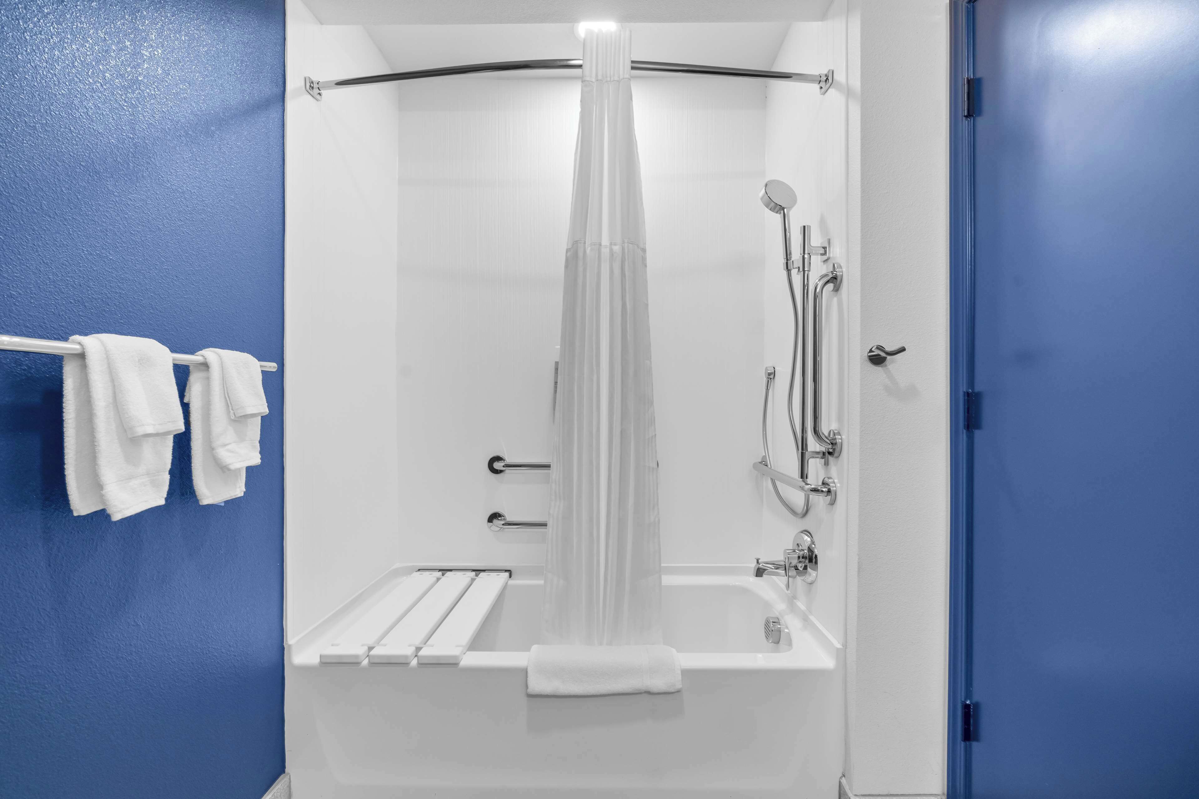 A modern bathroom with a bathtub, shower, and towel rack.