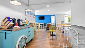 A modern kitchen with a blue island, wooden flooring, and a dining area with chairs and a table.