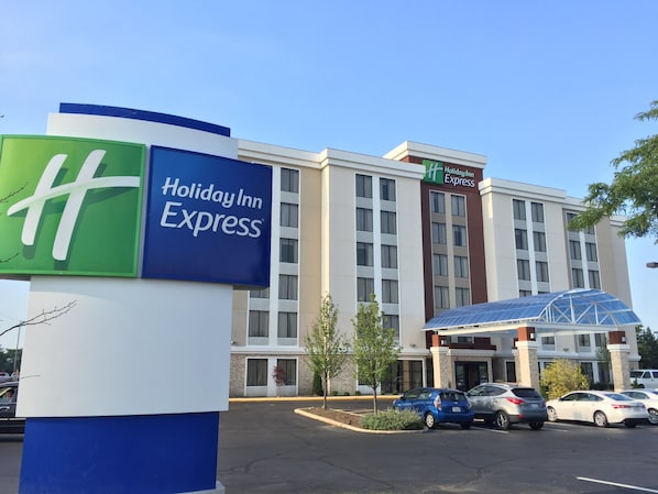 Un bâtiment de l’hôtel Holiday Inn Express, avec une enseigne bien visible, un parking et plusieurs voitures garées devant.