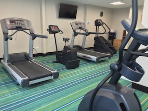 Un centre de remise en forme équipé de tapis de course et d’un vélo d’appartement.