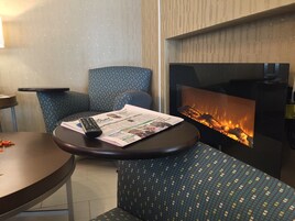 A cozy seating area with a fireplace, a table with a remote control, and a newspaper.