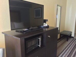 A dark wooden TV stand with a flat-screen TV, a coffee machine, and a microwave. - Holiday Inn Express Chicago NW - Arlington Heights by IHG (Arlington Heights)