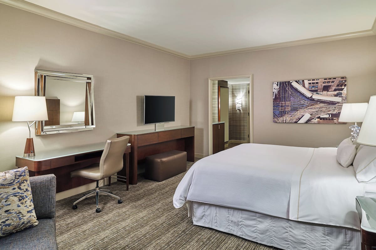 Une chambre d’hôtel avec un lit, un bureau, une chaise, une télévision et un tableau au mur.
