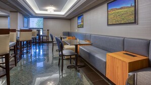 En modern hotelllobby med en sittgrupp, bord och ett stort fönster som ger utsikt över omgivningen.