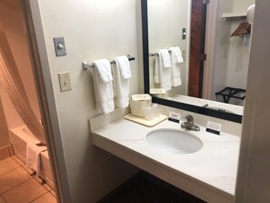 A bathroom with a white sink, a mirror, and multiple white towels hanging on a rack. - Navajoland Hotel of Tuba City (Tuba City)