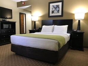 A hotel room with a large bed, two bedside tables with lamps, a flat-screen TV, a microwave, and a framed picture on the wall. - Navajoland Hotel of Tuba City (Tuba City)