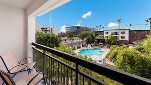 A balcony with two chairs, a swimming pool, and surrounding buildings. - Sonesta Select Tempe Downtown (Tempe)