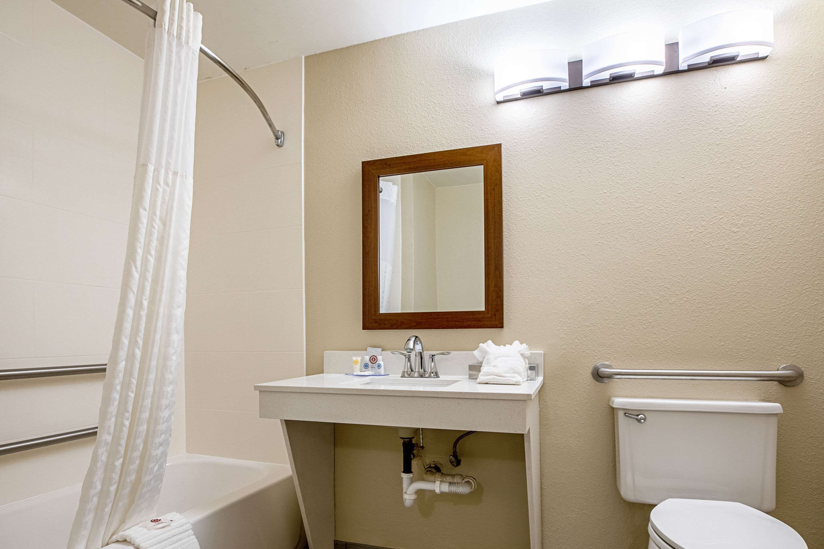 A bathroom with a bathtub, a sink, a mirror, and a toilet.