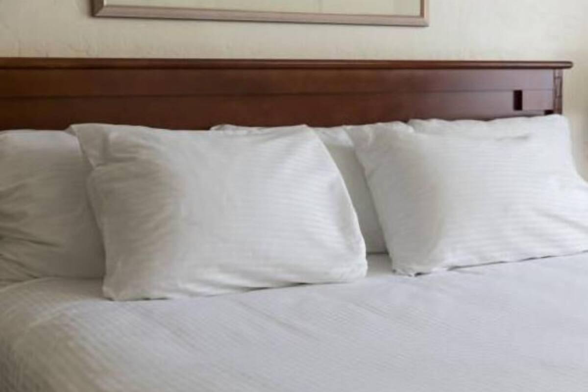 Una cama con ropa de cama blanca y cabecera de madera.