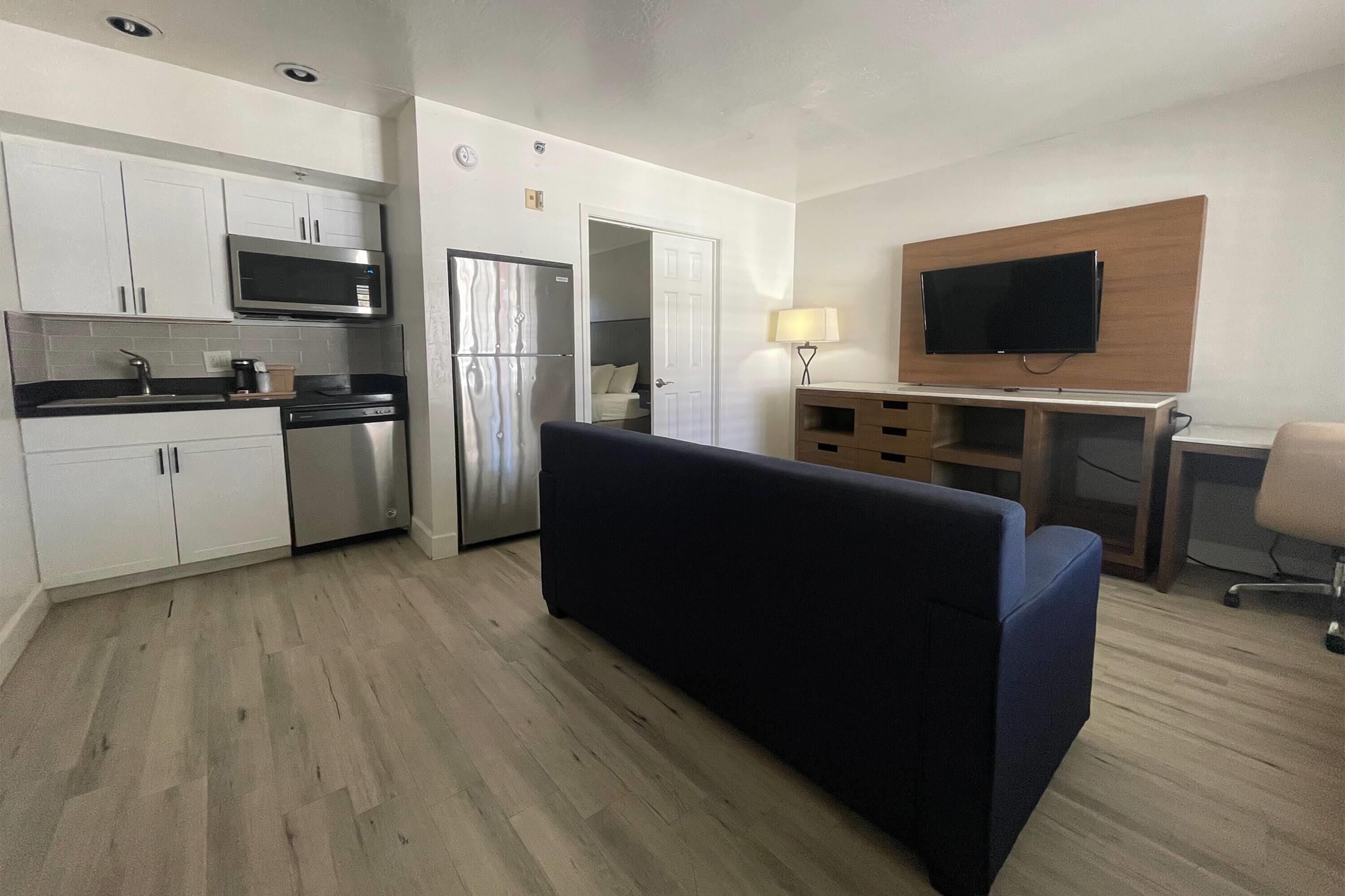 A compact kitchen with modern appliances, a sofa, a TV, and a desk area.