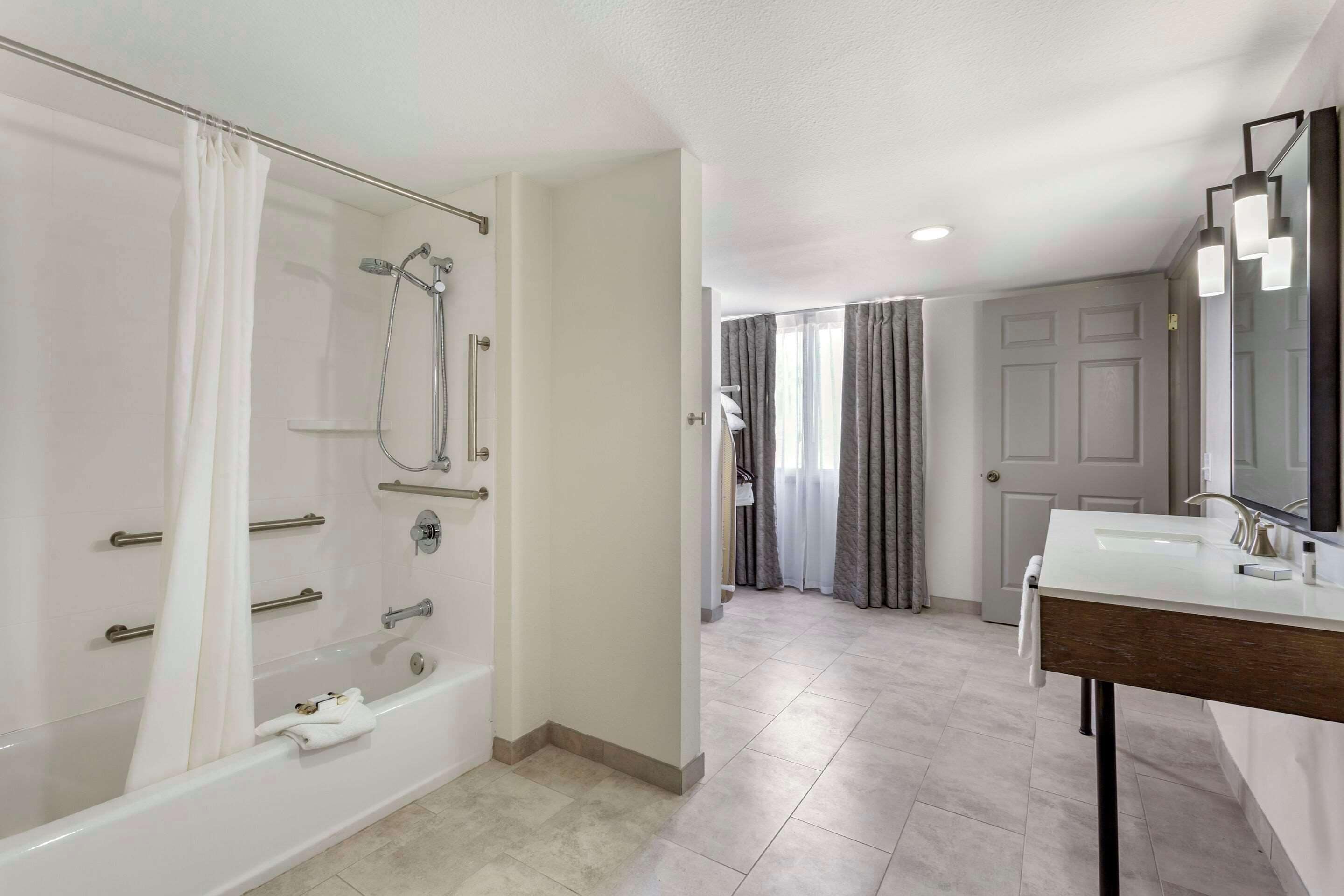 suite, 1 king bed, 2 person sofa bed, roll-in shower, accessible, non smoking | bathroom | combined shower/bathtub, free toiletries, hair dryer, towels