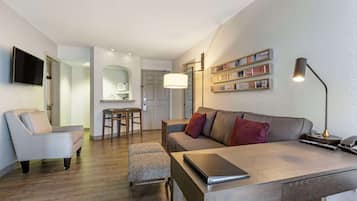 Una sala moderna con un sofá, una mesa de centro, un televisor y un comedor con mesa y sillas.