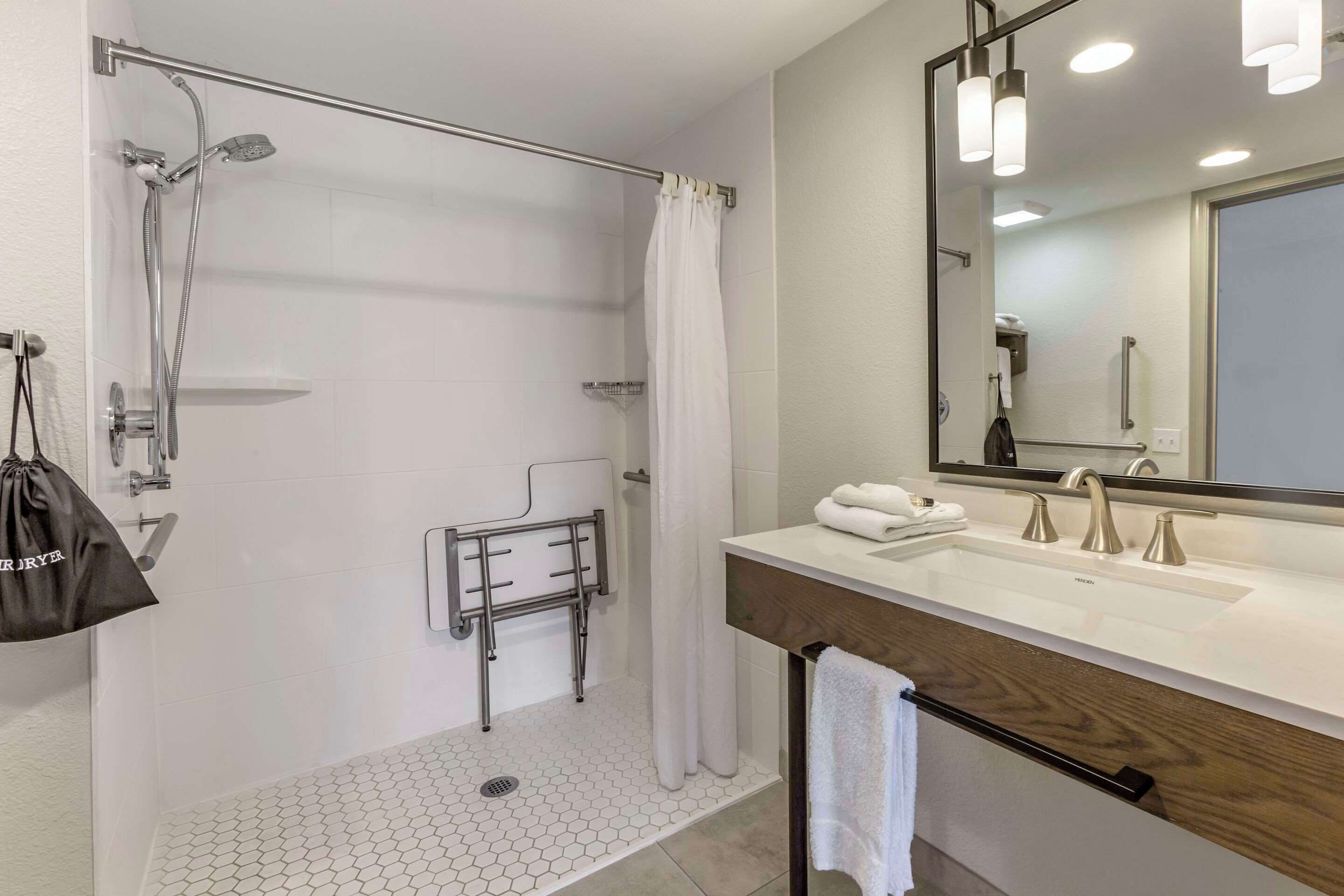 Un baño moderno con ducha, tocador con espejo y un perchero para toallas.