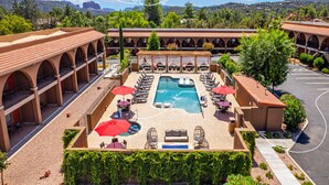 A hotel with a pool area, outdoor seating, and a view of the mountains.