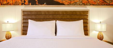 Una habitación de hotel con una cama grande, dos lámparas de noche y un mural con vistas a la montaña.