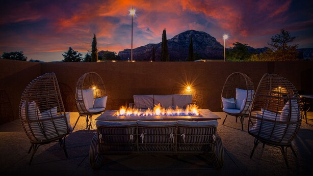 A patio area with a fire feature, wicker chairs, and a view of a mountain range. - GreenTree Inn Sedona (Sedona)