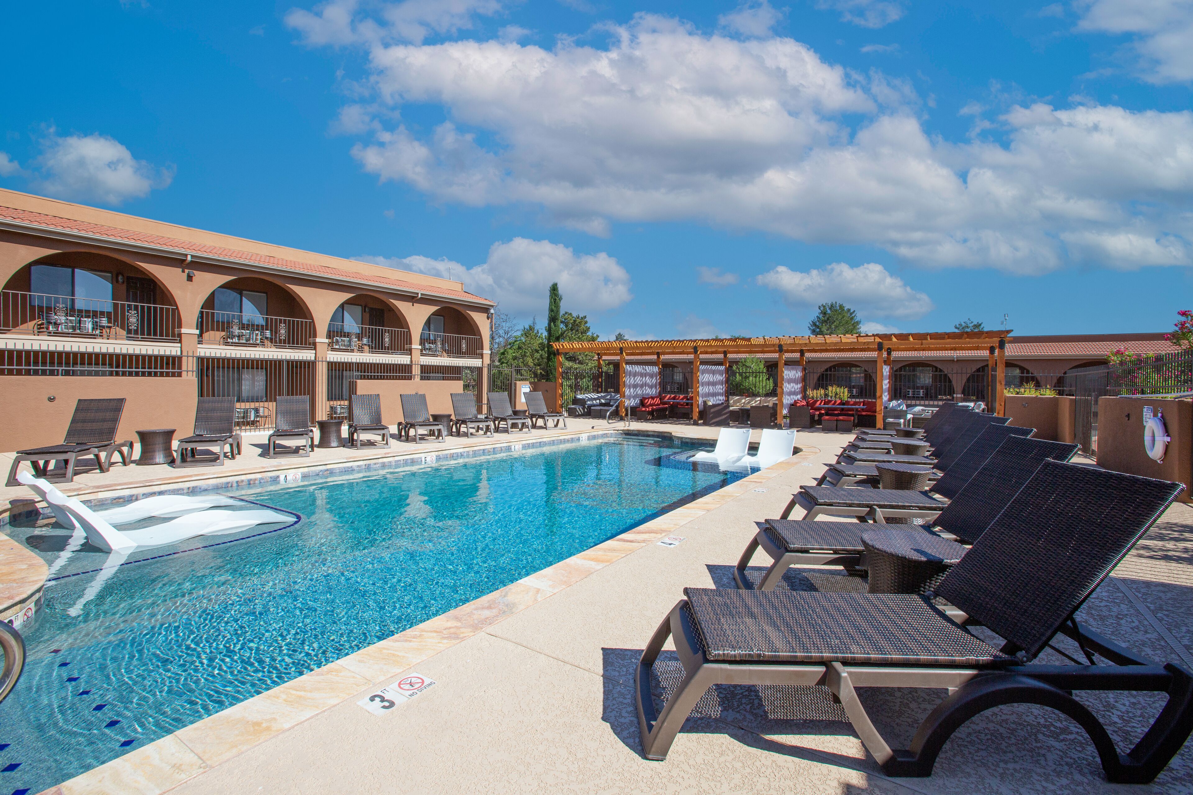 A pool area with lounge chairs and a building with arched windows.
