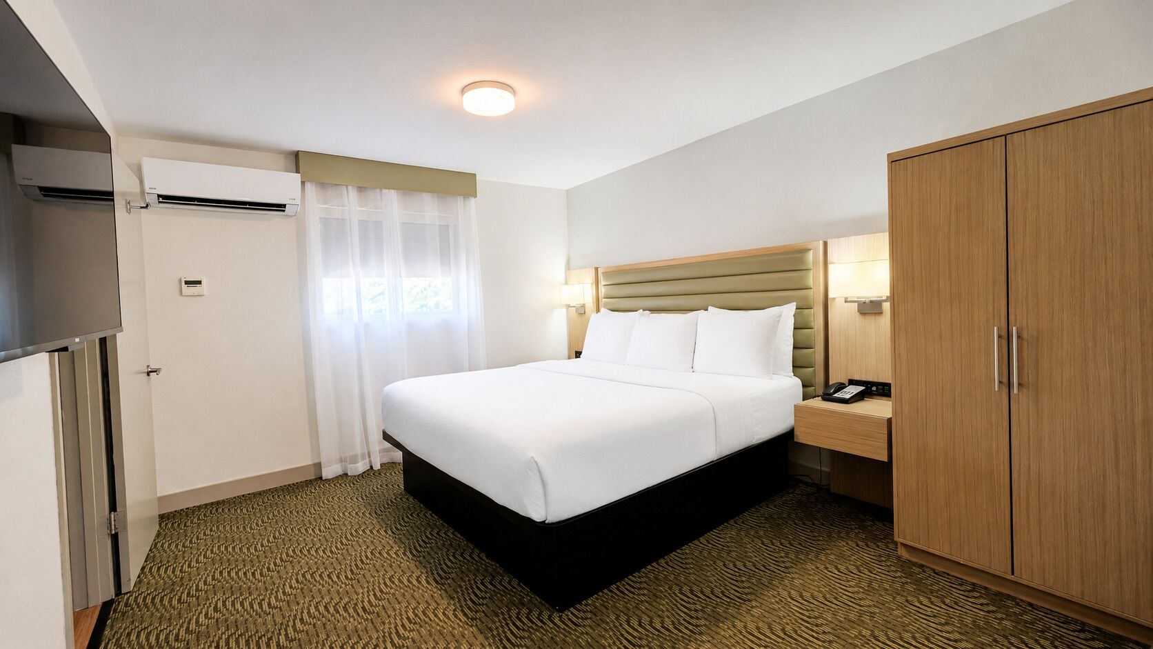 A hotel room with a bed, a nightstand, a wardrobe, and a television.