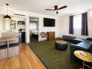 A modern living room with a sofa, a TV, a ceiling fan, and a dining area with a table and chairs. - GreenTree Inn Sedona (Sedona)