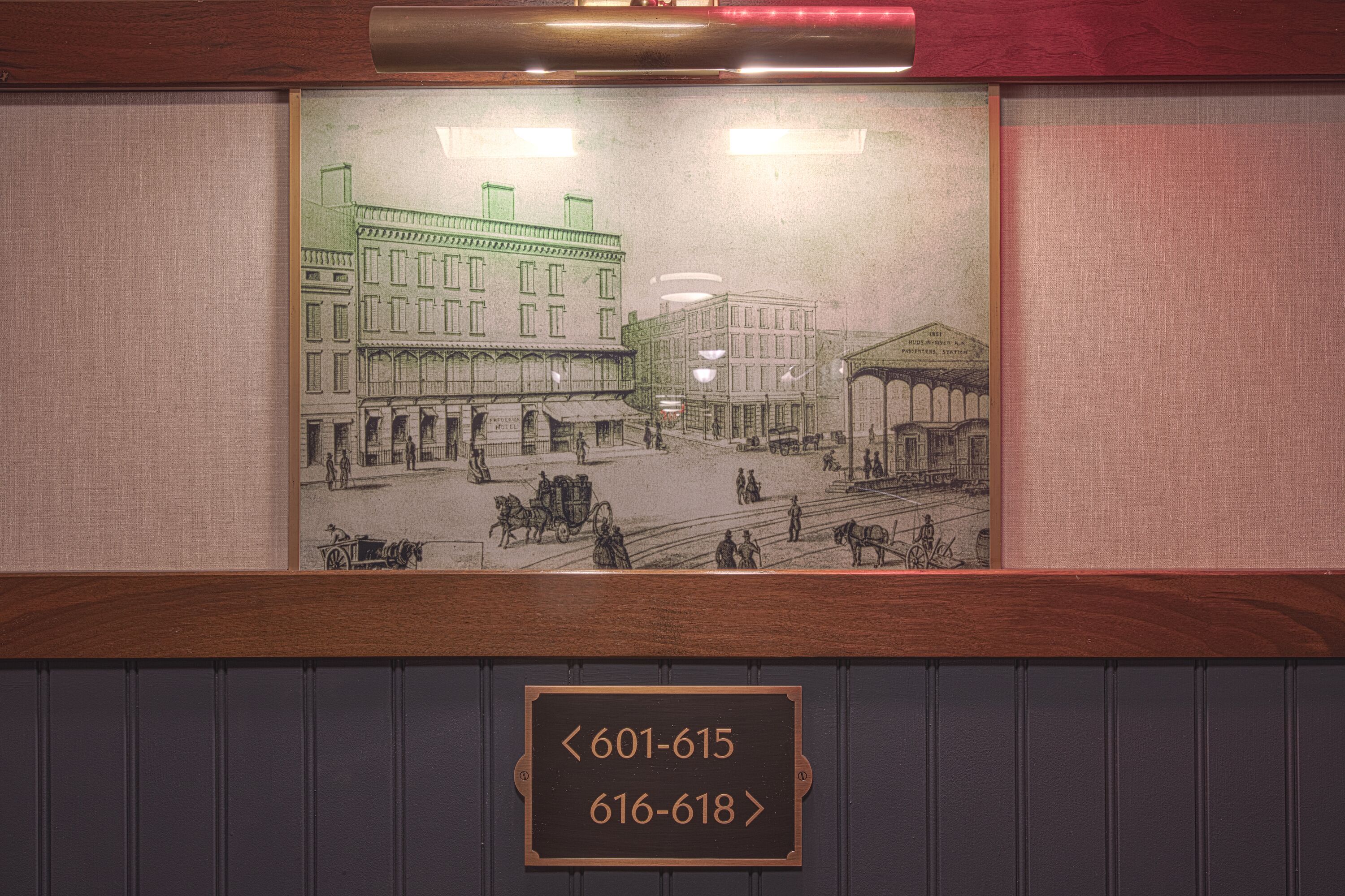 Une reproduction encadrée d’une scène de rue historique, avec une enseigne en bois en dessous affichant des numéros de téléphone.