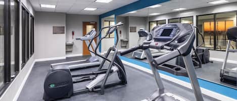 A fitness center with treadmills, ellipticals, and a mirrored wall.