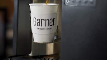 A coffee machine dispensing coffee into a cup labeled "Garner AN IHG HOTEL".