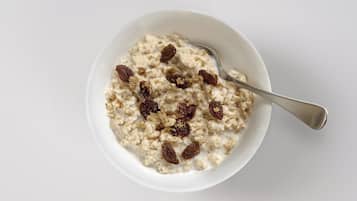 Un bol de porridge aux raisins et une cuillère.