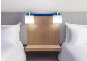 Una habitación de hotel con dos camas, un cabecero de madera y dos lámparas de noche.